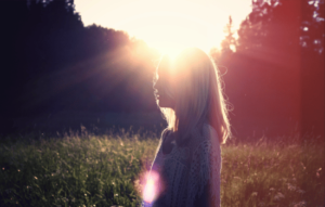 A woman in a sunny field looking relieved.